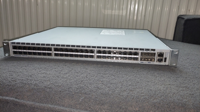 Photo of an Arista 7050TX-64 network switch, featuring 48 RJ45 ports, 4 SFP sockets, 2 RJ45 management ports and a USB port