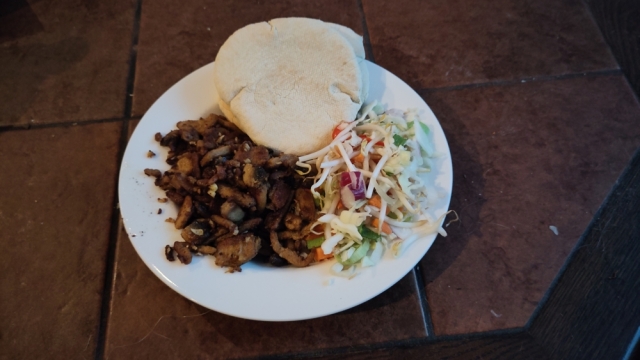 Foto van een bord met daarop shoarma, rauwkost en twee pitabroodjes