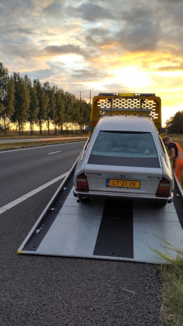  Zilvergrijze Citroën CX wordt op de vrachtwagen van de berger getrokken.
